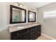 Bathroom vanity with double sinks, dark wood cabinets, and decorative mirrors at 7424 Snow Dr, Englewood, FL 34224