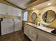 Bathroom featuring double vanity, granite counters, white cabinets, and washer and dryer at 810 Manchester Ct, Englewood, FL 34223