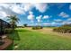 Manicured backyard featuring lush green grass and beautiful landscaping bordering a golf course at 934 Rotonda Cir, Rotonda West, FL 33947