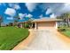 Inviting home featuring a well-manicured lawn, mature trees, and an attached two-car garage at 934 Rotonda Cir, Rotonda West, FL 33947