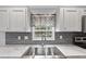 Close-up of the kitchen sink with a window view, showcasing the grey subway tile and the marble-look countertops at 2044 Culbreath Rd, Brooksville, FL 34601