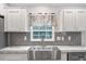 Close-up of kitchen sink, stainless steel appliances, marble countertop, and subway tile backsplash at 10215 Poplar St, New Port Richey, FL 34654