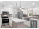 Modern kitchen with stainless steel appliances, white cabinetry, marble countertop island, and pendant lighting at 10215 Poplar St, New Port Richey, FL 34654