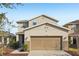 Two-story house with beige exterior, two-car garage, and landscaping at 10710 Southern Forest Dr, Riverview, FL 33578