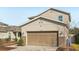 Two-story house with beige exterior, two-car garage, and landscaping at 10710 Southern Forest Dr, Riverview, FL 33578