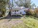 Backyard of home featuring mature landscaping, partially covered porch with ceiling fan, and green grass at 112 Nippino W Trl, Nokomis, FL 34275