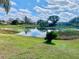 Scenic backyard view overlooking a tranquil lake with lush greenery and a serene, cloud-dotted sky at 7644 Arlight Dr, New Port Richey, FL 34655