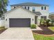 Charming two-story home with gray stucco exterior, dark garage door, and lush landscaping at 11143 Rising Mist Blvd, Riverview, FL 33578