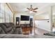 Cozy living area with a plush gray sofa, ceiling fan, and media console under a large TV at 11143 Rising Mist Blvd, Riverview, FL 33578