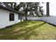 Backyard with grass area and mature trees, enclosed by a white vinyl fence at 1413 Sandalwood Dr, Plant City, FL 33563