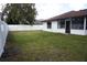 Backyard with a mix of grass and shaded areas, complemented by a white vinyl fence at 1413 Sandalwood Dr, Plant City, FL 33563