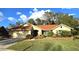 Single-story house with red tile roof, lush landscaping, and a paved driveway at 3633 Nettle Creek Ct, Holiday, FL 34691