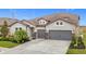 Two-story house with gray siding, stone accents, and a three-car garage at 11701 Brighton Knoll Loop, Riverview, FL 33579