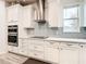 Modern kitchen with white cabinets, stainless steel appliances, and gray tile backsplash at 11701 Brighton Knoll Loop, Riverview, FL 33579