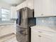 Stainless steel refrigerator in a white kitchen with gray tile backsplash at 11701 Brighton Knoll Loop, Riverview, FL 33579