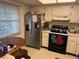 Kitchen boasts refrigerator, stove, and an adjacent dining area at 1415 Doolittle Ln # 107, Dunedin, FL 34698