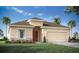 Tan house with brown roof, 2-car garage, and landscaping at 6036 Mangrove Creek Orch, Wimauma, FL 33598