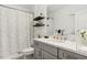 Modern bathroom with gray vanity, marble countertops, decorative shelves, and a shower-tub combo with curtain at 11658 Bluestone Ct, Parrish, FL 34219