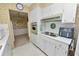 Cozy kitchen featuring white cabinets, vintage wallpaper, and retro green oven and stove top at 2167 Timber Ln, Clearwater, FL 33763