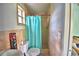 Cozy bathroom with a toilet and a shower behind a turquoise shower curtain at 1413 May St, Lutz, FL 33548