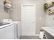 Bright laundry room with white appliances, gray wood-look flooring, and decorative shelving at 6072 Ballast Dr, Wimauma, FL 33598