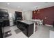 Modern kitchen featuring dark cabinetry, stainless steel appliances, and a granite island at 8680 Falling Blue Pl, Riverview, FL 33578