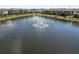 Wide aerial view of a serene pond and fountain surrounded by residential townhomes at 8680 Falling Blue Pl, Riverview, FL 33578