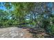 Scenic backyard with a bench overlooking a tranquil lake surrounded by lush greenery and mature trees at 1061 Owl Dr, Englewood, FL 34223