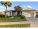 Tan one-story house with a two-car garage, palm trees, and well-maintained landscaping at 664 Silk Oak Dr, Venice, FL 34293