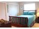 Cozy bedroom with wood furniture, bright turquoise bedding, and natural light from the window at 221 Malvern Dr, Venice, FL 34293