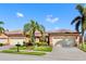 Tan two-car garage villa with lush landscaping and palm trees at 2096 Batello Dr, Venice, FL 34292