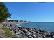 Oceanfront view with rocky shoreline and distant buildings at 708 Tamiami S Trl # 308, Venice, FL 34285