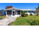 Charming single-story home with a screened porch, white trim, and blue shutters on a sunny day at 230 E Fray St, Englewood, FL 34223