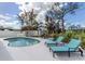 A free-form pool surrounded by lounge chairs, a table setting, palm trees, and white vinyl fencing at 514 Palm Ave, Nokomis, FL 34275