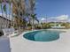 An outdoor pool with a white bench, table setting with chairs, two lounge chairs, and palm trees at 514 Palm Ave, Nokomis, FL 34275