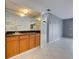 Stylish bar area with mirrored backdrop, wooden cabinets, and sleek countertops next to a spacious living area at 766 Avenida Estancia # 196, Venice, FL 34292