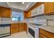 Functional kitchen with white appliances, wood cabinetry, and a view into the adjacent room at 766 Avenida Estancia # 196, Venice, FL 34292