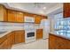 Well-lit kitchen with white appliances, wood cabinets, and tile backsplash for easy maintenance at 766 Avenida Estancia # 196, Venice, FL 34292