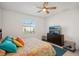 Bedroom boasts a dresser with TV, ceiling fan, window view, and tiled flooring at 19045 Moscato Ct, Venice, FL 34293