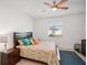 Bedroom with ceiling fan features a colorful bedspread, throw pillows, and tile flooring at 19045 Moscato Ct, Venice, FL 34293