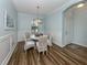 Well-lit dining room showcases wainscoting, a stylish chandelier, and a round table with seating for four at 235 Cassano Dr, Nokomis, FL 34275