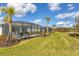 Landscaped backyard with screened enclosure at 25544 Royal Tern Ln, Englewood, FL 34223