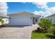 Single-story home with a two-car garage, brick driveway, manicured lawn, and a tile roof at 25544 Royal Tern Ln, Englewood, FL 34223