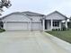 Two-story house with a three-car garage and landscaped lawn at 15467 Maynard Ave, Port Charlotte, FL 33953