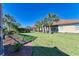 Spacious backyard with lush lawn, palm trees, and landscaping at 620 Lakescene Dr, Venice, FL 34293