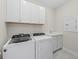 Laundry room with Whirlpool washer and dryer and white cabinets at 26056 Seastone Dr, Englewood, FL 34223