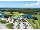 Aerial view of a golf course community with clubhouse, lush greens, and a lake at 816 Derbyshire Dr, Venice, FL 34285