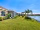 Backyard with screened patio, lush lawn, and lake view at 21621 Winter Park Ct, Venice, FL 34293