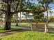 Relaxing park bench under a sprawling tree on a tree-lined Venice street at 614 May Apple Way, Venice, FL 34293