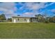 Rear view of a single story house with gray siding, a large yard, and screened patio at 4130 Rock Creek Dr, Port Charlotte, FL 33948